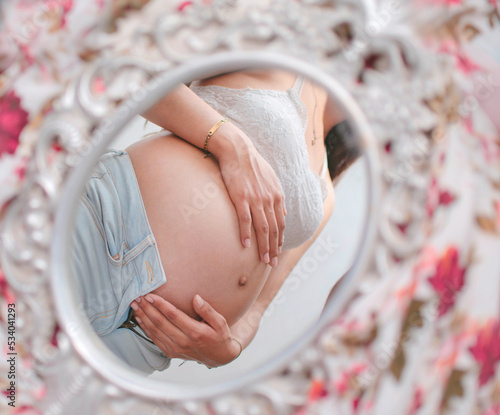 Canvastavla Reflejo en el espejo de una mujer caucasica embarazada tocando su vientre con la