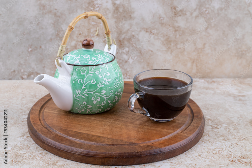 A wooden board with teapot and a cup of tea A wooden board with teapot and a cup of tea