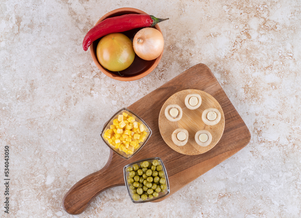 A wooden board of various vegetables on a marble background
