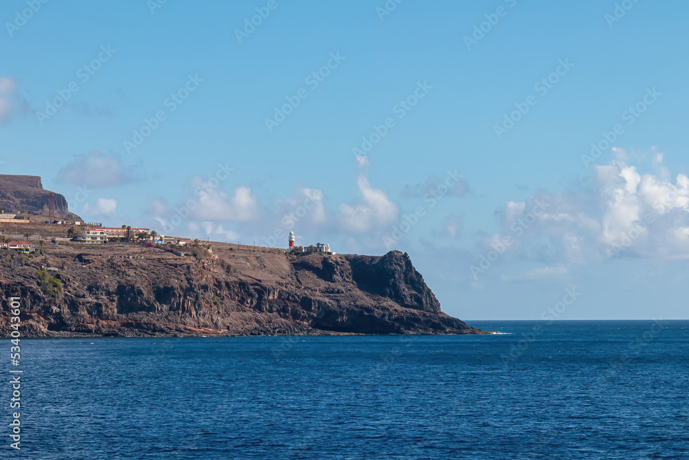 Panoramic view from the ferry on the lighthouse of San Sebastian de La Gomera, La Gomera and Tenerife, Canary Islands, Spain, Europe. Island hopping vacation in spring and summer. Beautiful cliffs