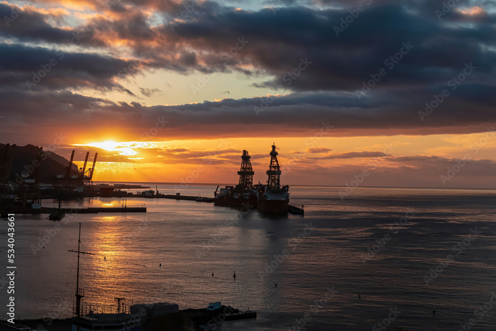 Panoramic view during sunset of the port Santa Cruz de Tenerife, Tenerife, Canary Islands, Spain, Europe. Silhouette of the ship yard and several cranes can be seen. Romantic atmosphere