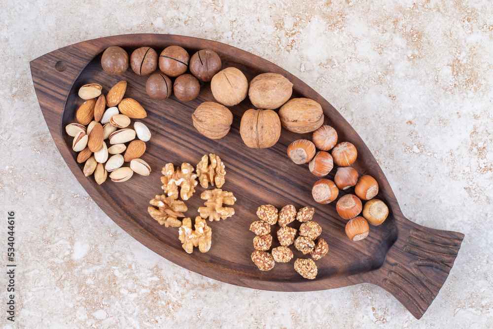 Tray with assorted nuts and chocolate balls on marble background
