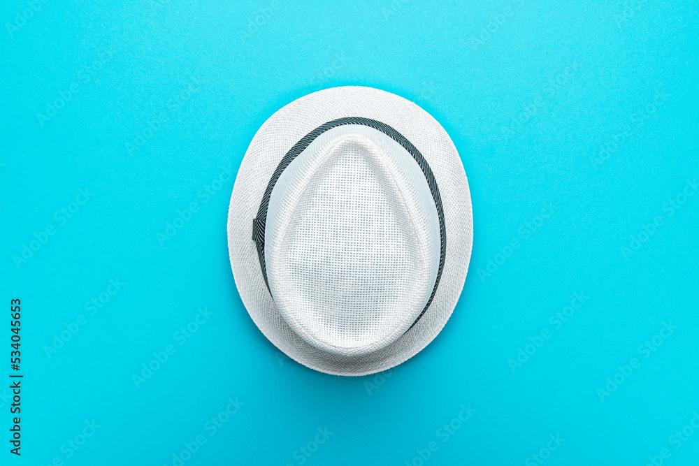 Top view of trilby over turquoise blue background. Flat lay top-down composition of white trilby hat. Minimalist flat lay photo of white hat in the center with copy space to the sides. Top view of trilby over turquoise blue background. Flat lay top-down composition of white trilby hat. Minimalist flat lay photo of white hat in the center with copy space to the sides.