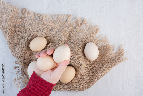 Hand taking eggs from a bundle on a piece of cloth on marble background