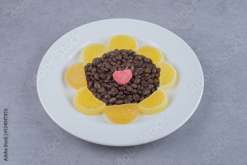 Coffee beans and marmelades on a platter on marble background