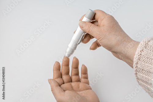 Close-up Of elderly woman Hand Holding Sugar Level Checking Machine