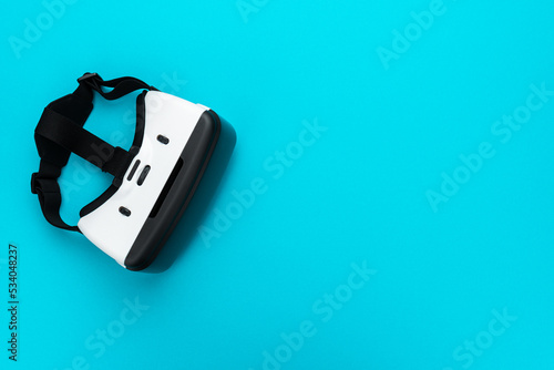 Virtual reality headset on turquoise blue background. Top view of VR helmet with copy space. Minimalist flat lay photo of white vr headset.