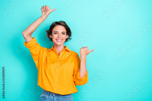 Photo of adorable gorgeous cute girl bob hairstyle wear yellow blouse directing empty space isolated on turquoise color background