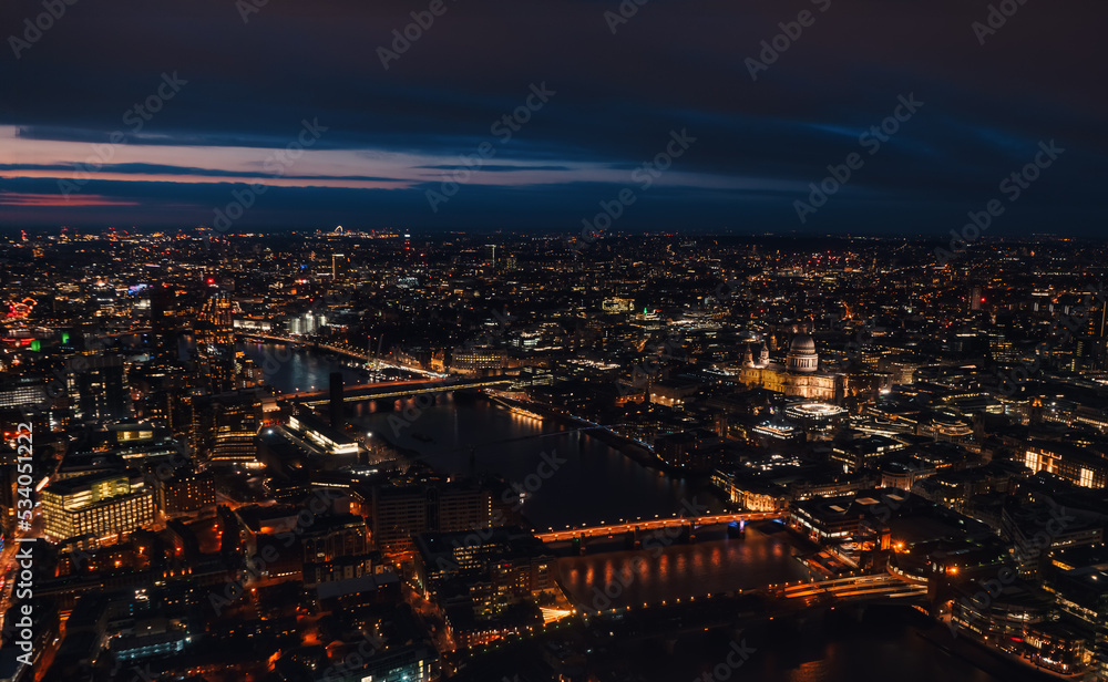 Aerial view of north east part of London, in evening. St Pauls Cathedral visible over river Thames