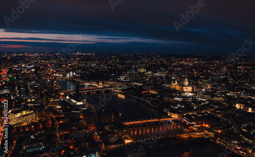 Aerial view of north east part of London, in evening. St Pauls Cathedral visible over river Thames