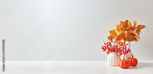 Home interior with decor elements. Colorful autumn leaves in a vase on a light background. Mock up for displaying works