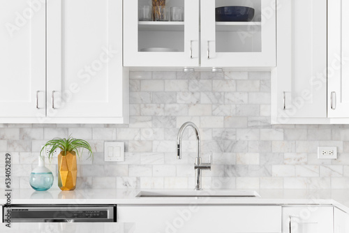 A kitchen sink detail shot with white cabinets, marble subway tile backsplash, and cozy decor.