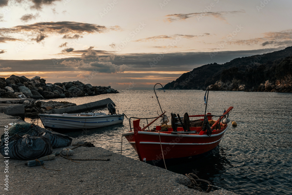 Greek fishing harbor scene with boats, at sunrise on a beautiful tranquil summer day in july