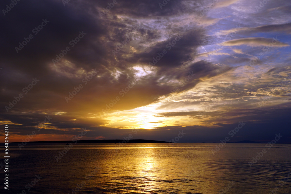 Sun behind clouds above the beautiful golden sea surface