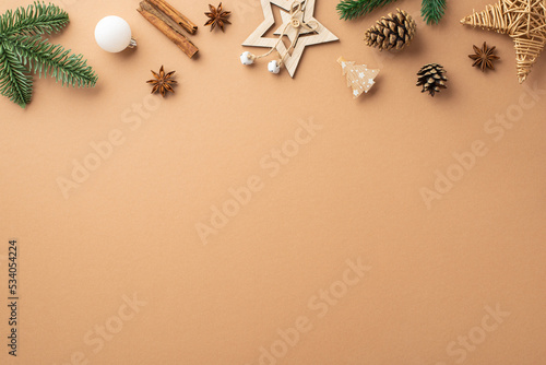 Christmas decorations concept. Top view photo of star wood ornaments bauble pine cones spruce branches anise and cinnamon sticks on isolated beige background with empty space