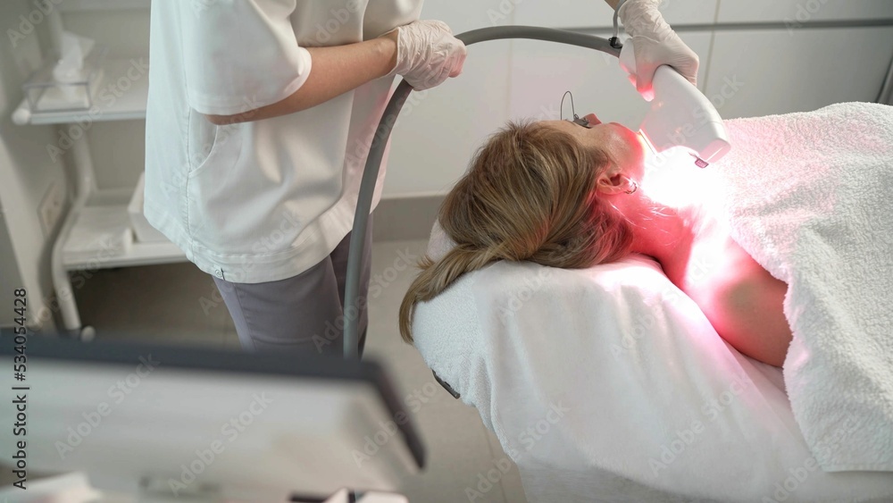 The cosmetologist performs the procedure on the skin of the client's face with special equipment. Female client receiving face skin rf lifting procedure from professional beautician on modern. The cosmetologist performs the procedure on the skin of the client's face with special equipment. Female client receiving face skin rf lifting procedure from professional beautician on modern.