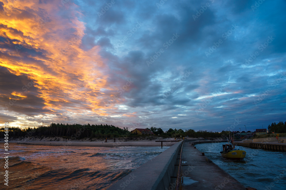 Obraz na płótnie Wschód słońca w Rowach na Bałtykiem, rybacy wypływający w morze. w salonie