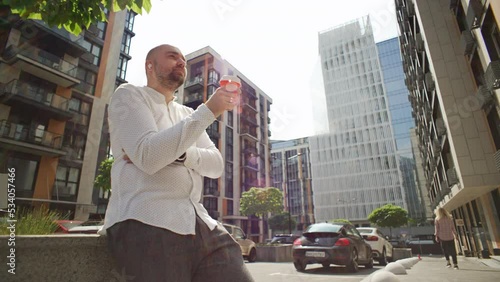 A businessman listens to music in headphones that fall out. The manager drinks coffee during the break and dances. High quality 4k footage photo