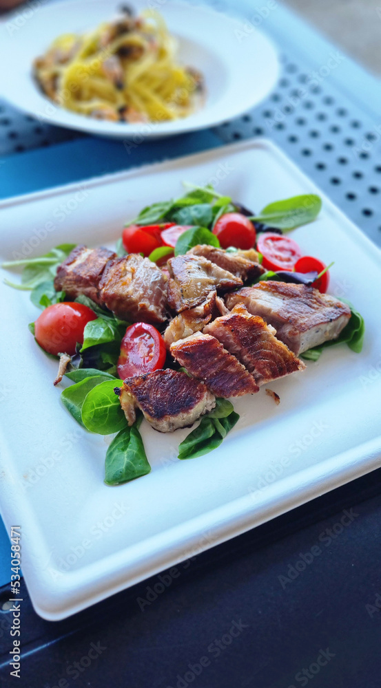 Φωτογραφία tagliata di tonno fresco servita in un piatto di carta con pomodorini e insalata