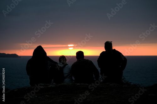 A group of people watching the sunset from the coast of Ruiloba, Cantabria, Spain 