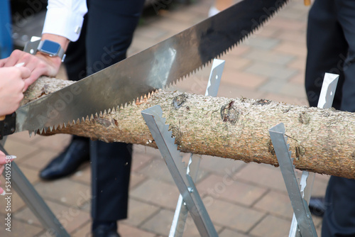 Details eines Sägebock mit Baumstamm und Säge bei einer Hochzeit.