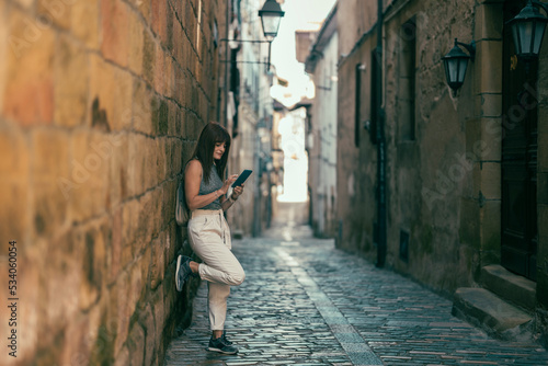 woman leaning against a stone wall using a cell phone photo