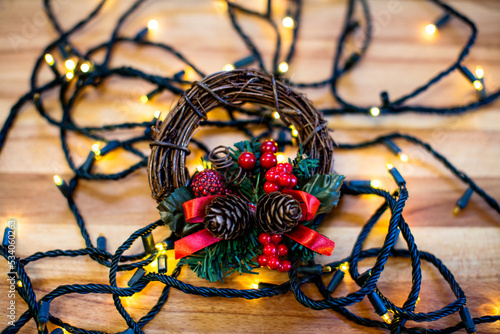 Christmas wreath on christmas lights and wooden table.