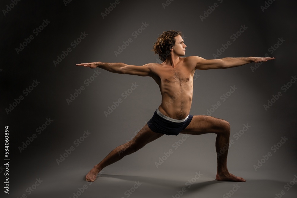Shirtless young man doing Warrior 2 pose