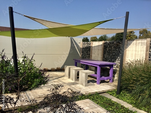 Lounge area in summer garden. Appeltern is the Netherlands' largest garden idea park. Relaxing garden with purple table and three stone chairs near gabion wall photo