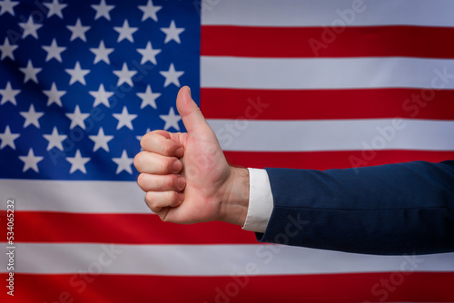 Thumbs up hand in approval with the United States flag in the background. Support for American politics and the American way of life. Vote for America