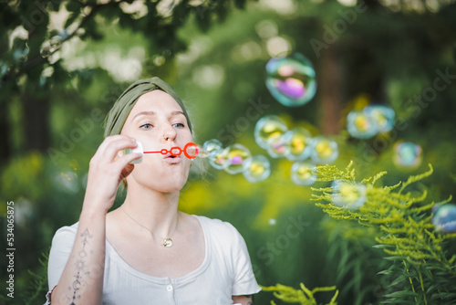 happy alternative   spiritual looking hipster girls makes soap bubbles   blows them in the air outside in the garden with green nature background to have fun 