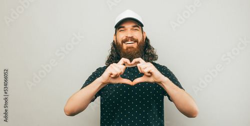 Portrait of cheerful young bearded man showing heart gesture with hands. photo