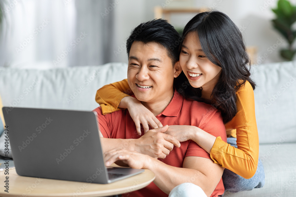 Loving chinese man and woman using computer together at home Loving chinese man and woman using computer together at home