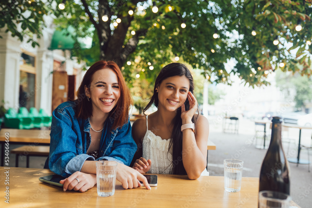 Two female friends browsing in mobile phones at street cafe. Two female friends browsing in mobile phones at street cafe.