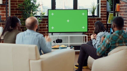 Soccer fans watching football match using greenscreen on television, enjoying sport game tournament on isolated copyspace. Looking at blank mockup template and background on tv.