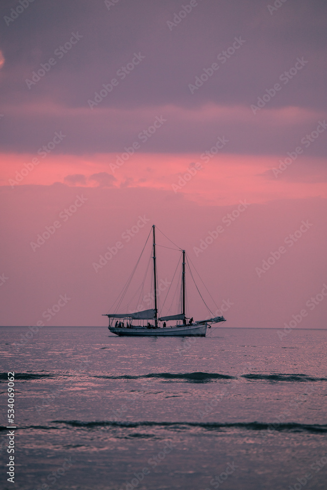 Fototapeta premium Atardecer rosa en el mar con barco en el horizonte