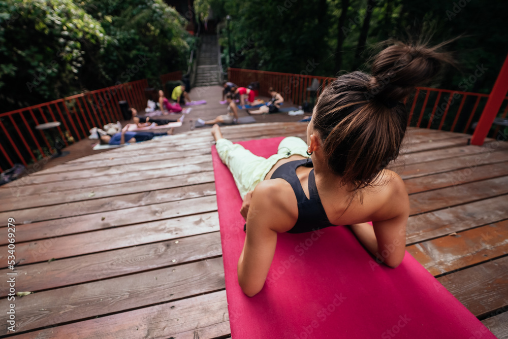 Naklejka premium Group of young sporty people practicing yoga lesson with instructor,