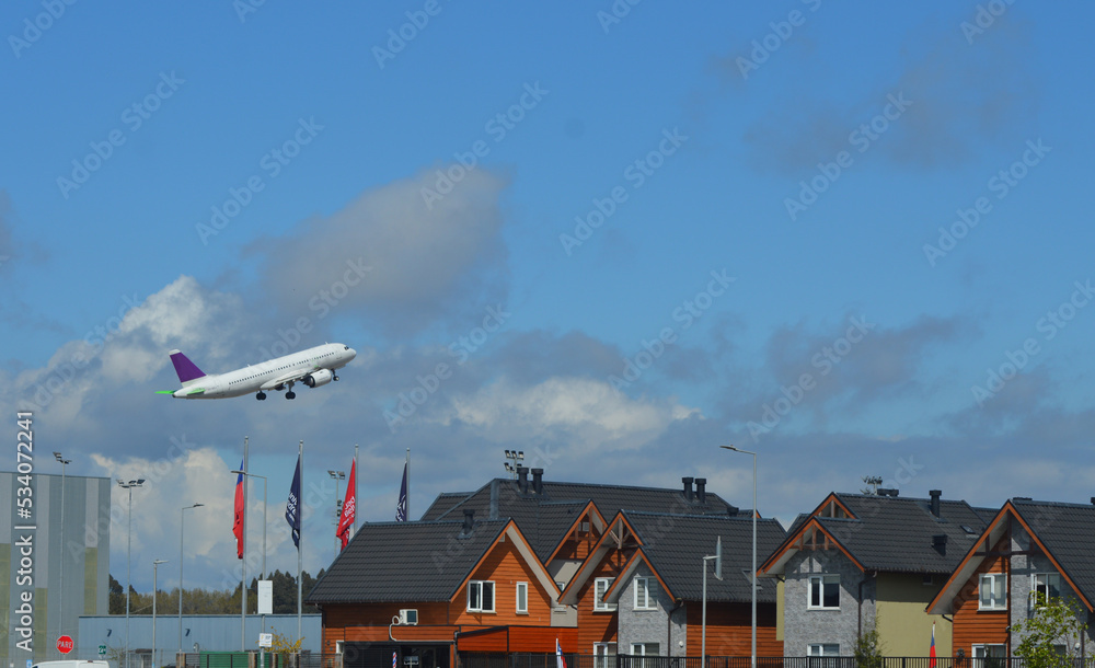 Naklejka premium passenger plane clearing from an airport near a housing estate