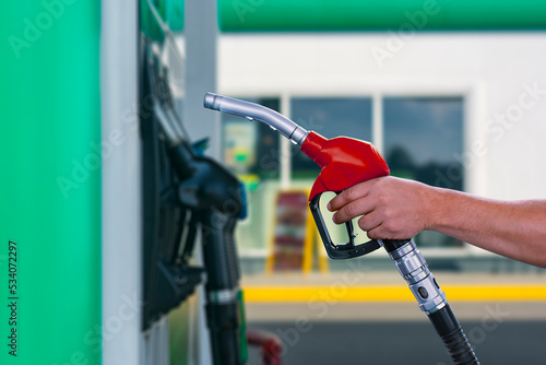 Man holds a refueling gun in his hand for refueling cars. Gas station with diesel and gasoline fuel close-up.