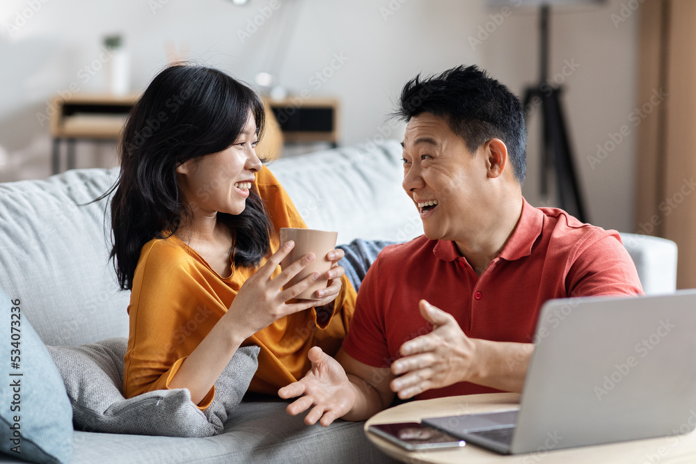 Cheerful korean couple planning vacation, using laptop Cheerful korean couple planning vacation, using laptop