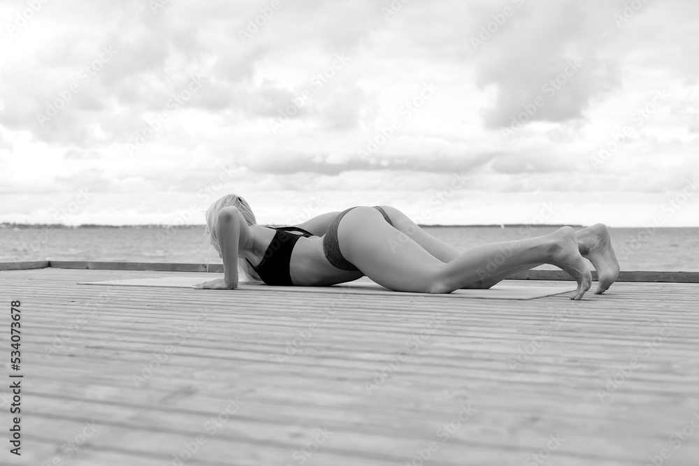young woman practices yoga on the beach