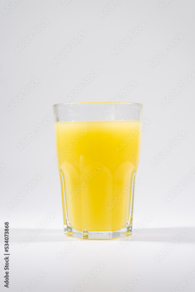 fresh yellow cold fruit juice with lemon, ice, straw isolated