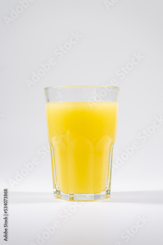 fresh yellow cold fruit juice with lemon, ice, straw isolated