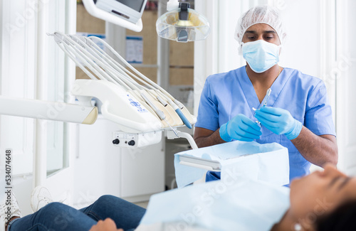 Portrait of professional hispanic stomatologist preparing sterile dental functional diagnostic instruments for work