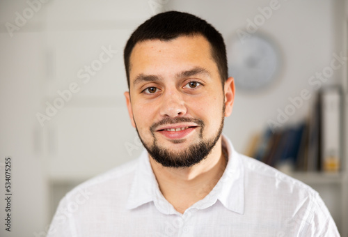 Portrait of cheerful man standing in his workplace in office and looking at camera.
