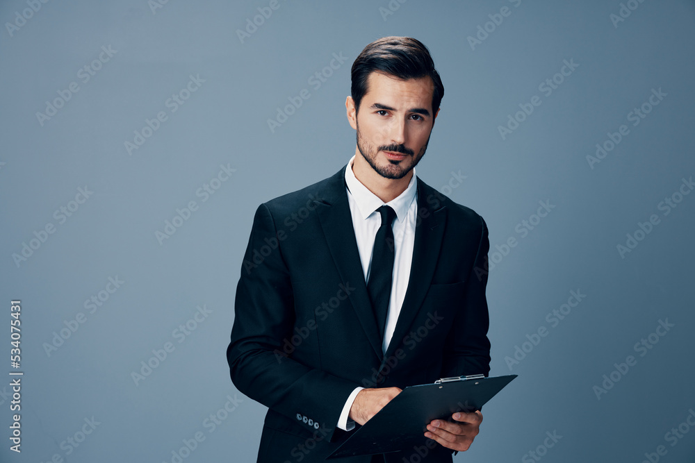 Portrait of a business man in a stylish suit smile with tie beautiful face on a blue isolated background with a tablet in his hands. Business concept young businessman startup copy place Portrait of a business man in a stylish suit smile with tie beautiful face on a blue isolated background with a tablet in his hands. Business concept young businessman startup copy place