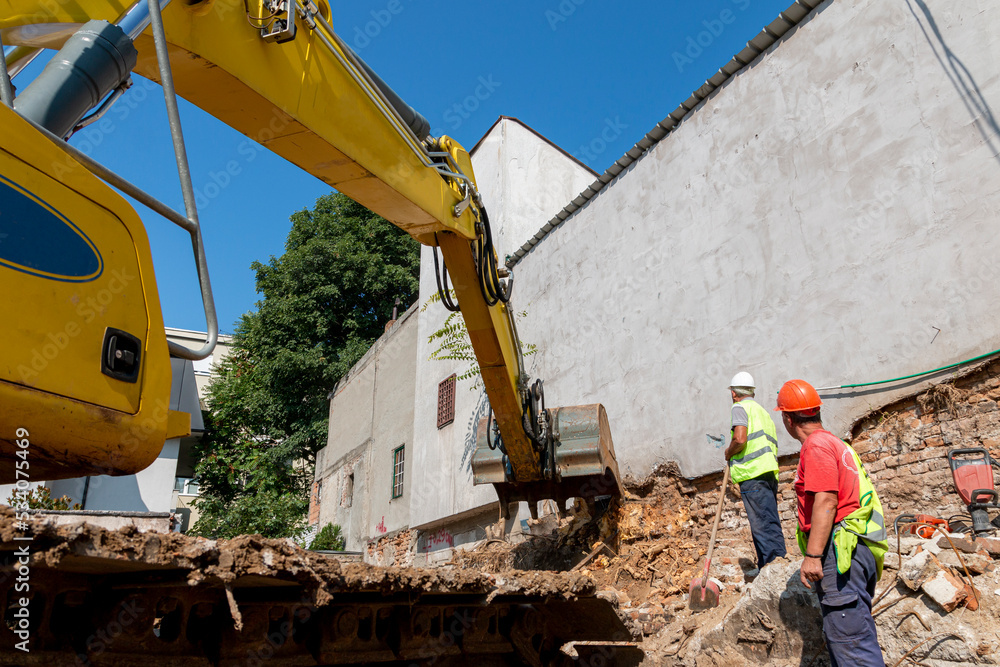 Obraz premium Site manager standing at the construction site of a private property, supervising, inspecting or overseeing the work progress.Process of demolition of old building dismantling. 