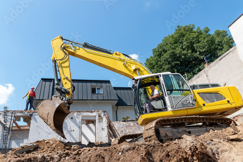 Process of demolition of old building dismantling. Excavator breaking house. Destruction of dilapidated housing for new development