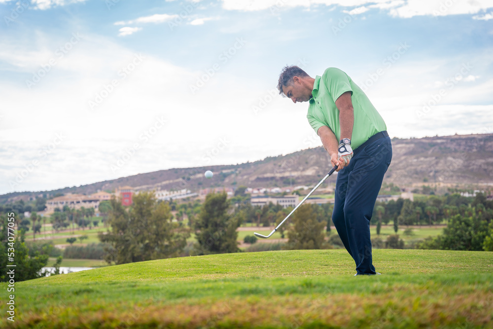 Handsome young man playing golf hitting the ball onto the green Handsome young man playing golf hitting the ball onto the green