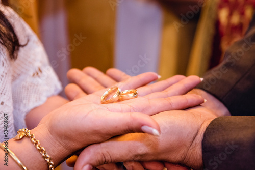 two hands of bride and groom holding a pair of rings